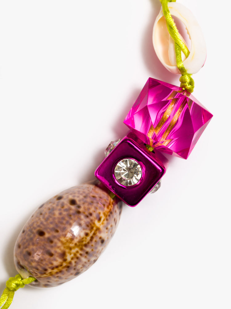Close up view of a keychain with pink acrylic and rhinestone beads, a painted cowrie shell and a large cowrie at the bottom.