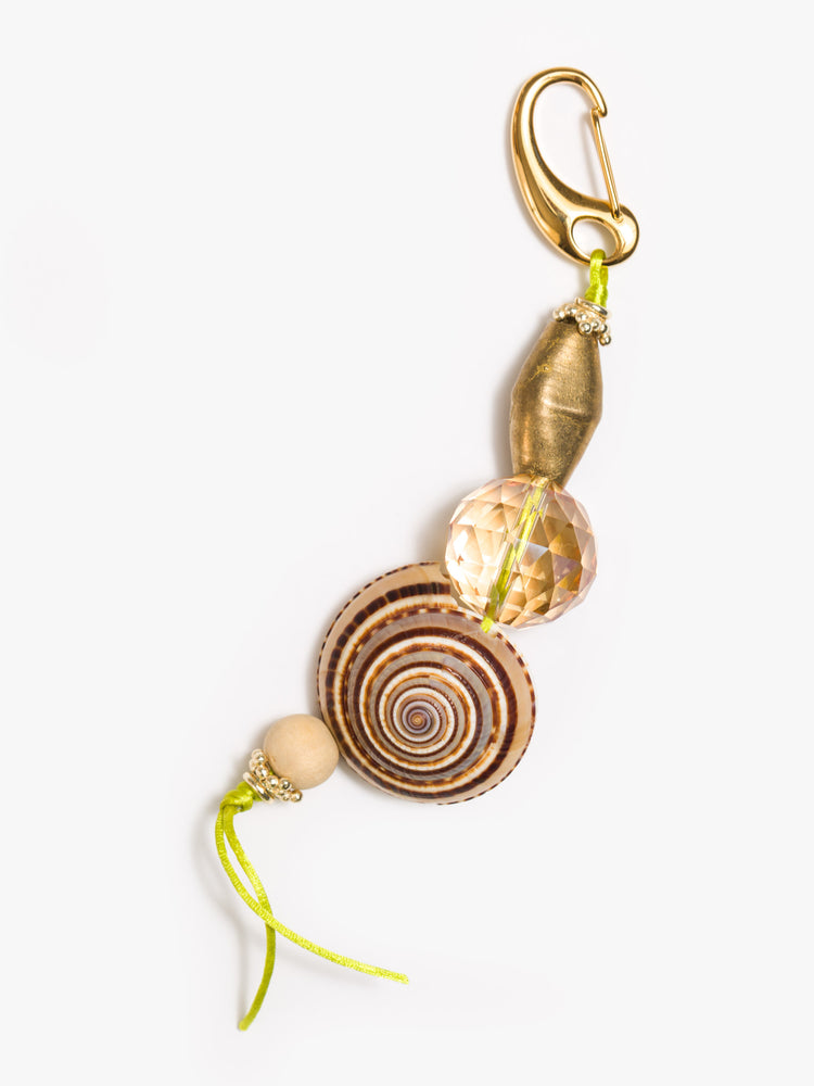 Flat view of keychain with a large sundial shell and beads made from brass, glass crystal and wood. 