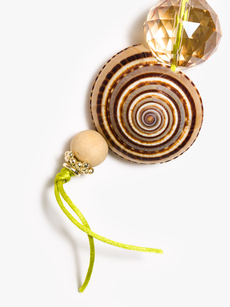 Close up view of keychain with a large sundial shell and beads made from brass, glass crystal and wood. 