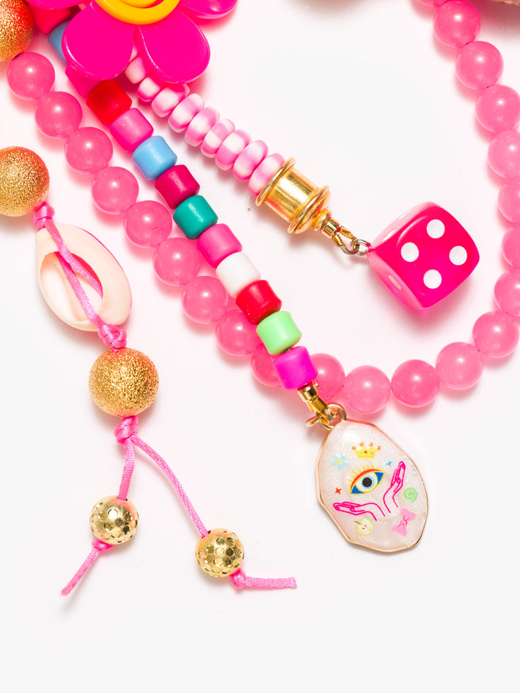 Close up view of a bag charm with mixed beads in shades of pink, shells, dice beads and a smiling flower.