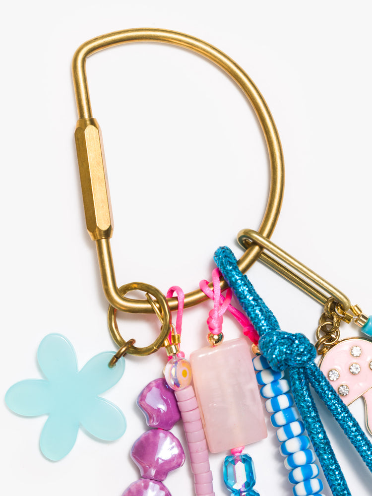 Clasp view of a bag charm with mixed beads in shades of purple, blue, pink and pearl, with shell, flower and mushroom charms. 
