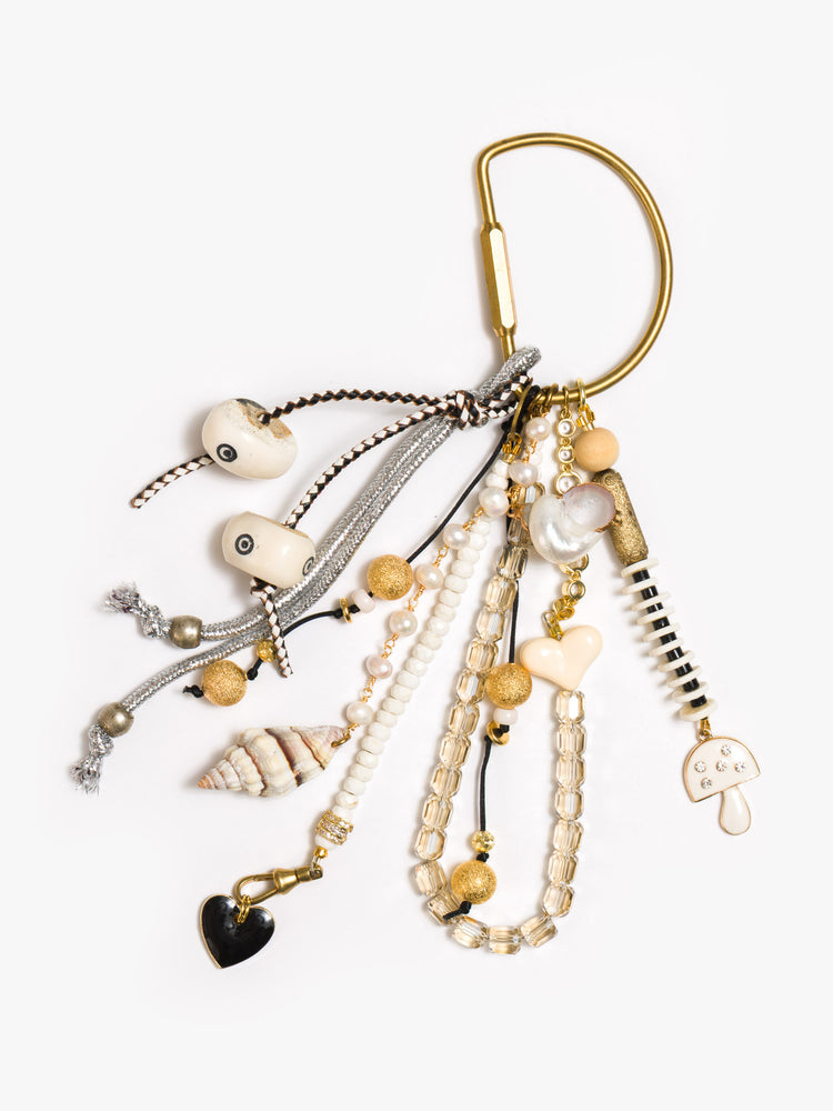 Flat view of a bag charm with mixed beads in shades of black, white and gold, with heart and mushroom charms. 