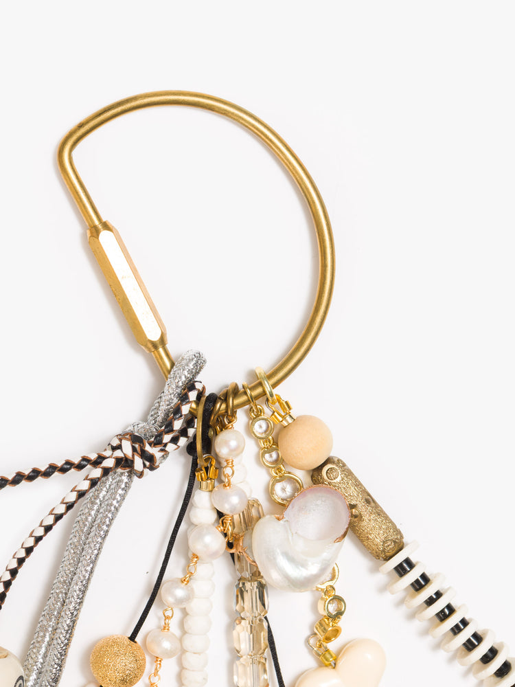 Close up view of a bag charm with mixed beads in shades of black, white and gold, with heart and mushroom charms. 