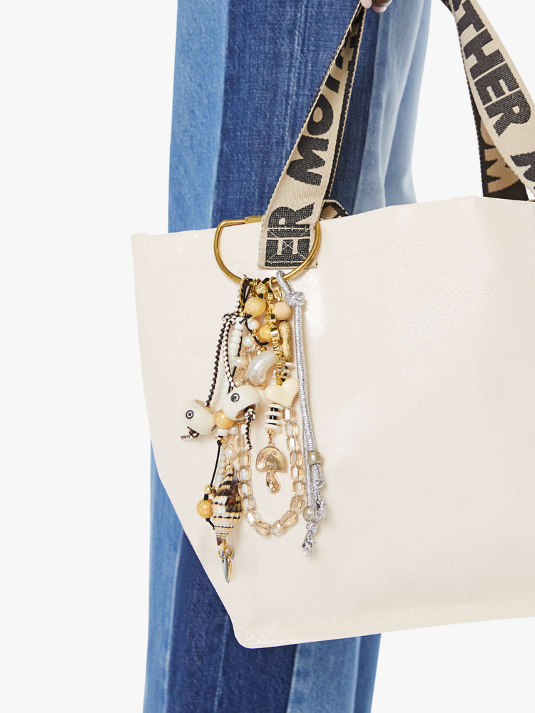 On bag view of a bag charm with mixed beads in shades of black, white and gold, with heart and mushroom charms. 