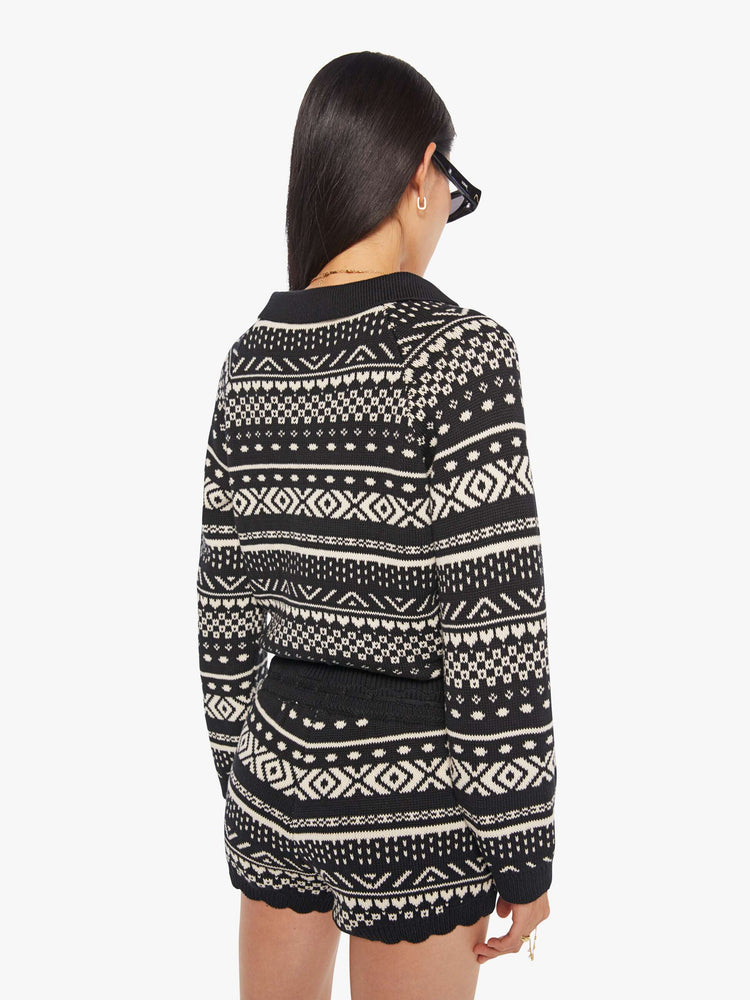 Back view of a woman in a black and off-white  top cable knit-inspired design, and features a buttoned V-neck, a front patch pocket, ribbed hems and a cropped fit.