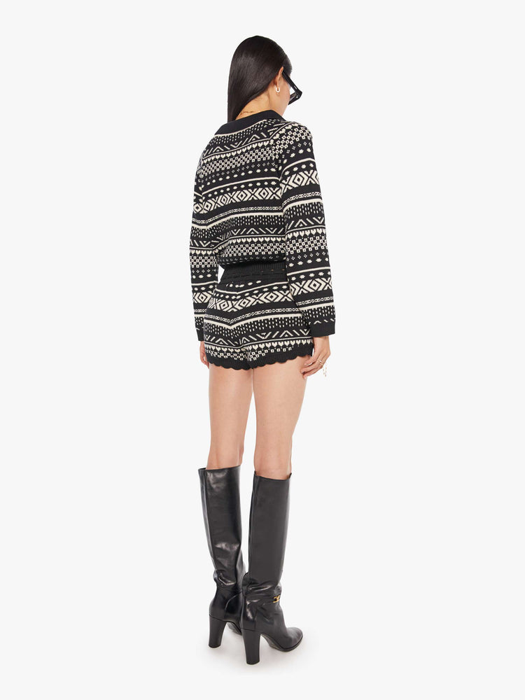 Back view of a woman in a black and off-white cable knit-inspired design, and feature a drawstring waistband, scalloped hems and an extra-short fit.