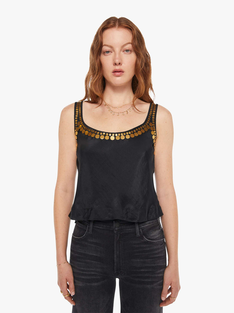 Front view of a woman in a  black tank with gold beaded details along the neck and sleeves, and features a deep scoop neck and a cropped boxy fit.