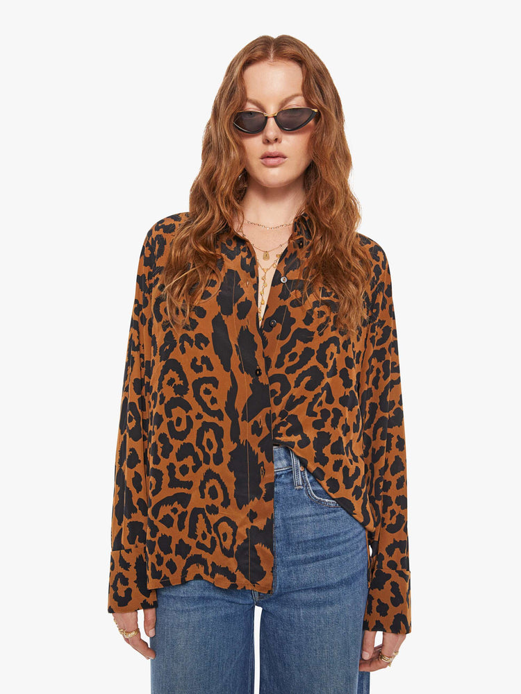 Front view of a woman in a button up leopard print, and features long balloon sleeves and a loose fit.