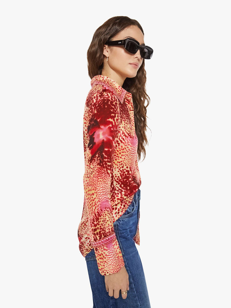 Side view of a woman in a top with abstract pink floral print with a V-neck, long sleeves and a narrow fit.