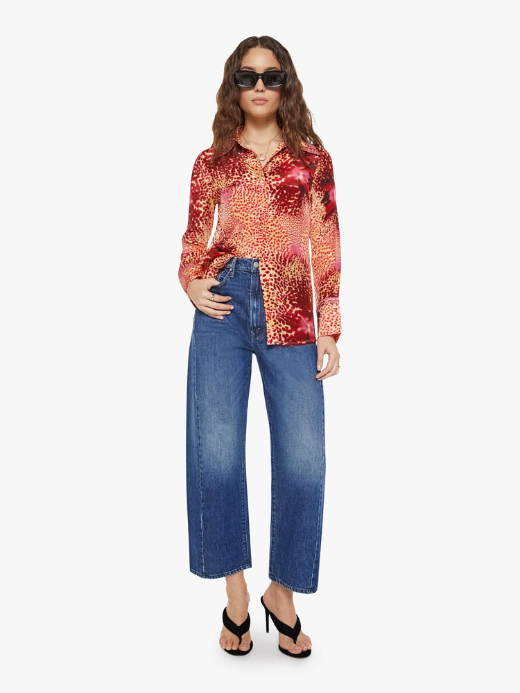 Full body view of a woman in a top with abstract pink floral print with a V-neck, long sleeves and a narrow fit.