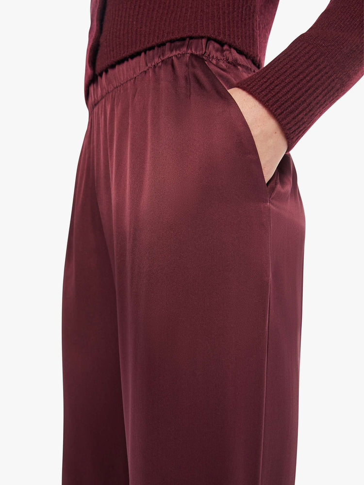 Close up view of a woman in wide leg silk pants with a high rise, side slit pockets and a loose straight leg.