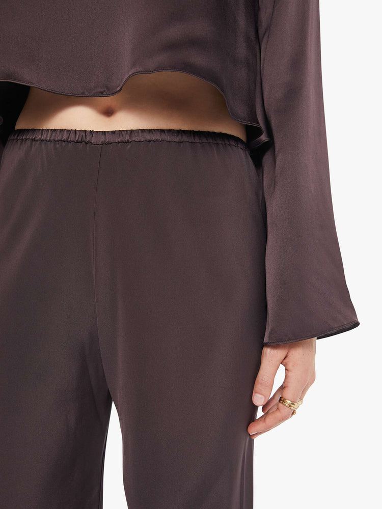 Close up view of a woman in dark brown pants with a high rise and a loose straight leg. 