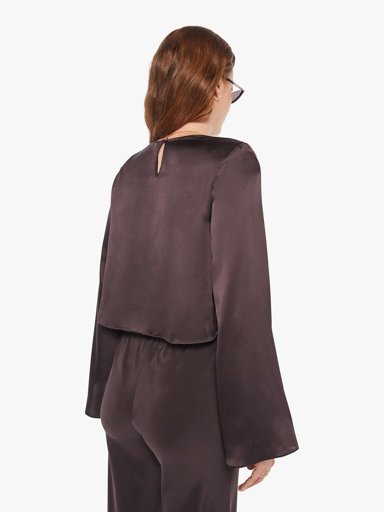 Back view of a woman in a oak brown color blouse with long bell sleeves, a cropped hem and loose fit.
