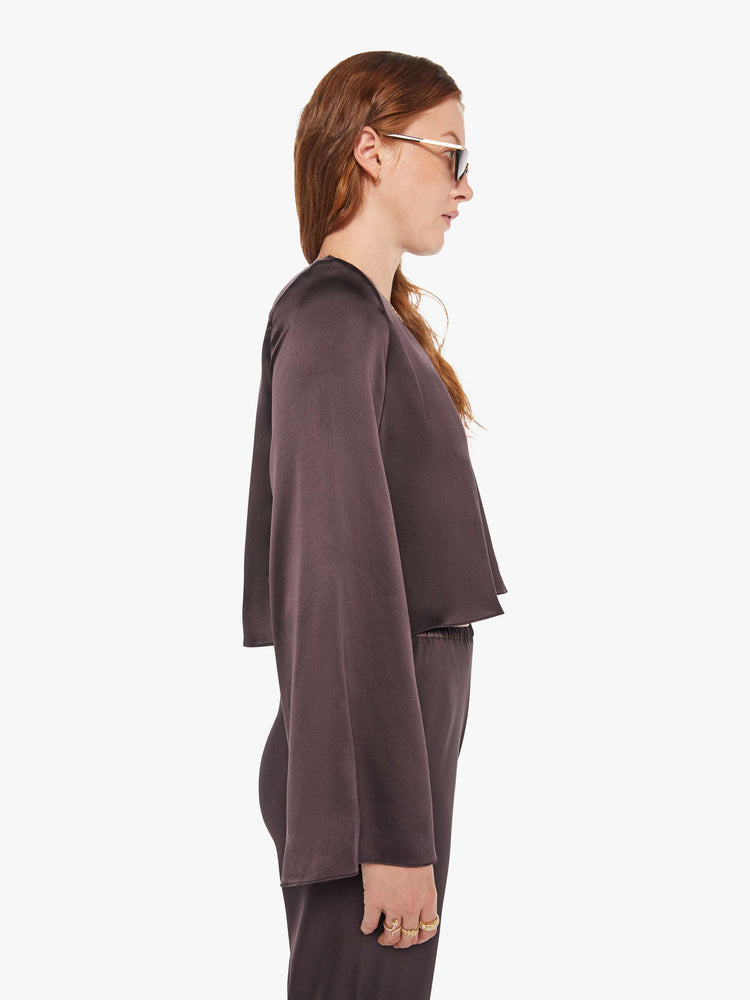 Side view of a woman in a oak brown color blouse with long bell sleeves, a cropped hem and loose fit.