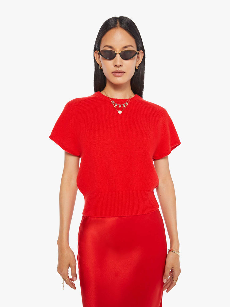 Front view of a woman in  bright red, the short-sleeve sweater is designed with a crewneck, ribbed hem and a slightly cropped fit.