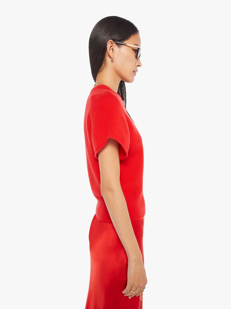 Side view of a woman in  bright red, the short-sleeve sweater is designed with a crewneck, ribbed hem and a slightly cropped fit.