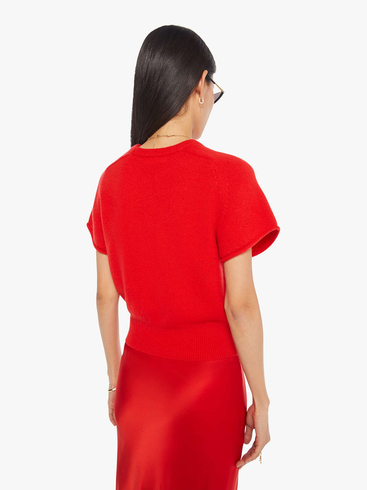 Back view of a woman in  bright red, the short-sleeve sweater is designed with a crewneck, ribbed hem and a slightly cropped fit.