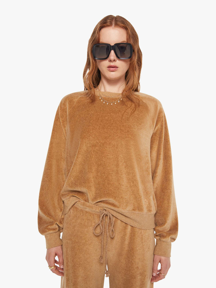 Front view of a woman in a heather camel sweatshirt with ribbed hems and a loose fit.