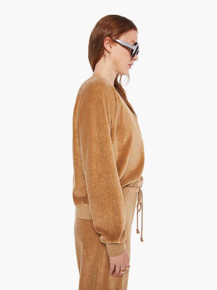 Side view of a woman in a heather camel sweatshirt with ribbed hems and a loose fit.