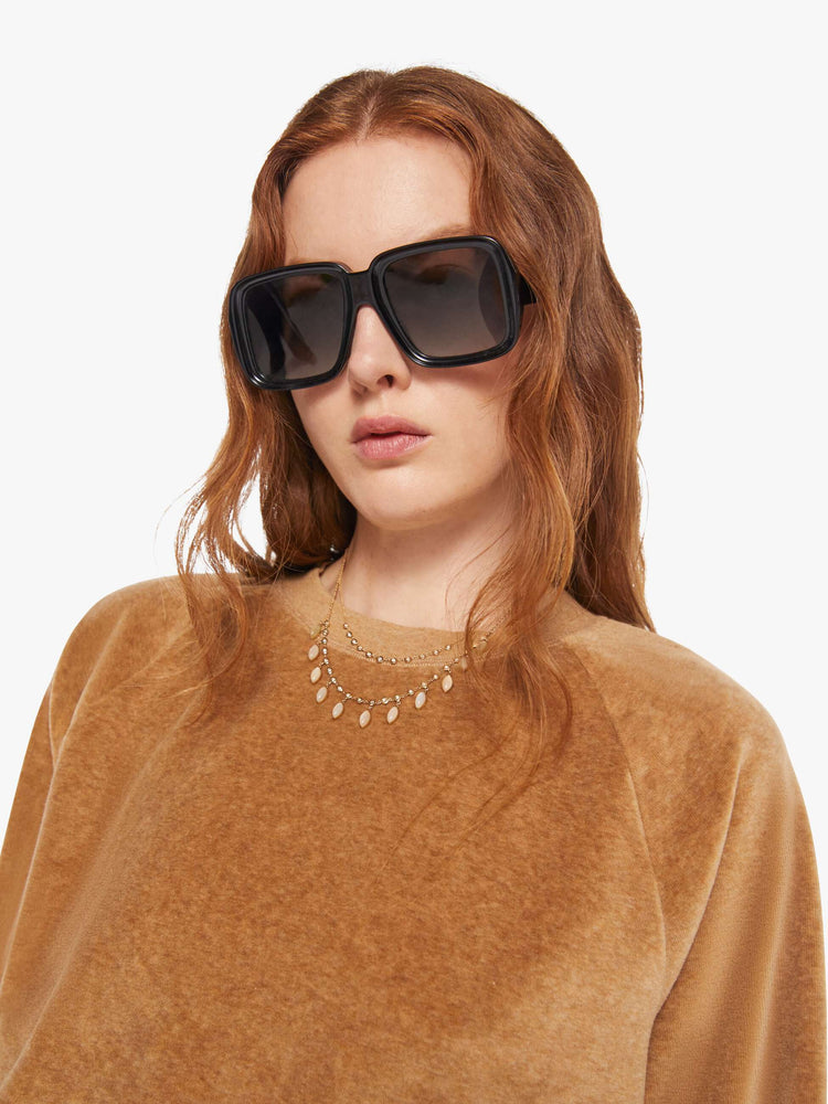 Close up view of a woman in a heather camel sweatshirt with ribbed hems and a loose fit.