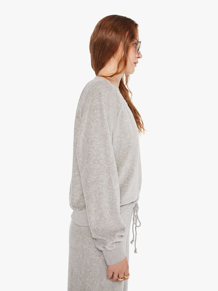 Side view of a woman in a heather grey sweatshirt with ribbed hems and a loose fit.