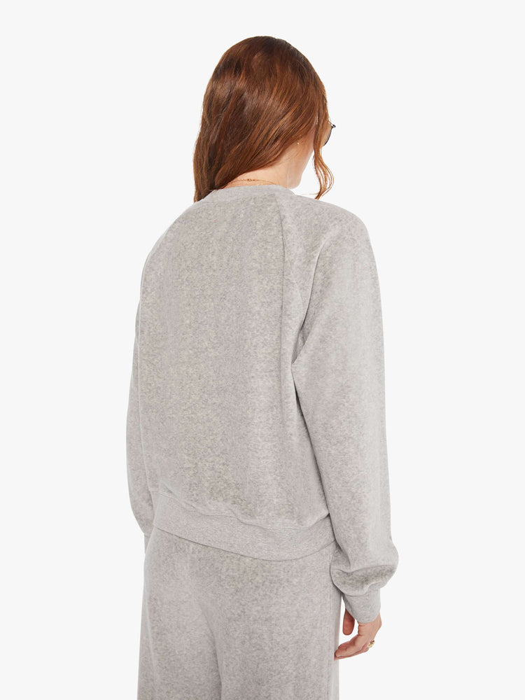 Back view of a woman in a heather grey sweatshirt with ribbed hems and a loose fit.