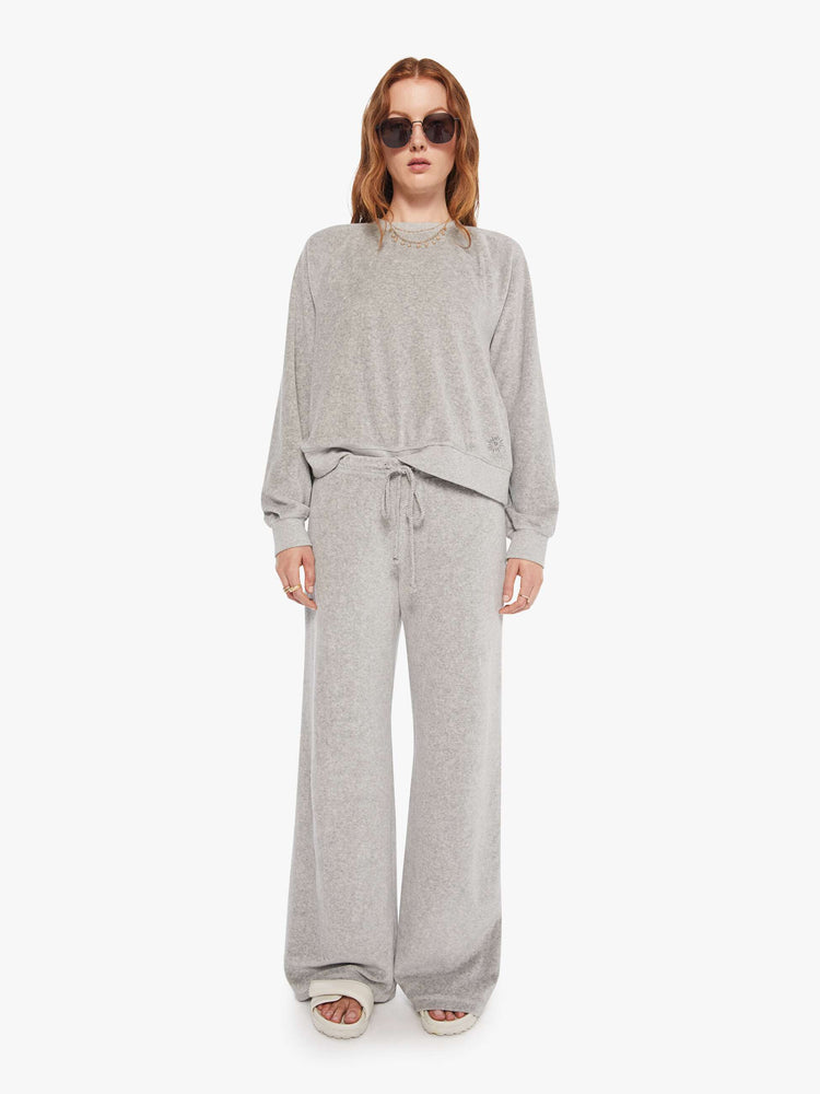 Full body view of a woman in a heather grey sweatshirt with ribbed hems and a loose fit.