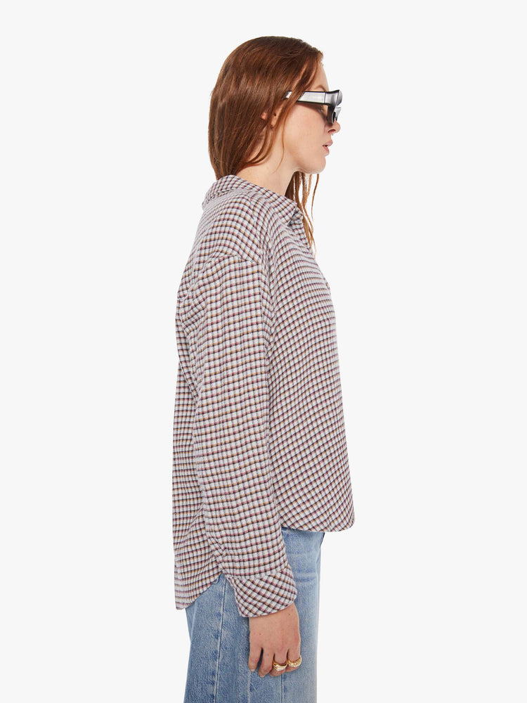 Side view of a woman in a white and baby blue checker print long sleeve shirt is designed with drop shoulders, a front patch pocket, curved hem and slightly cropped fit.