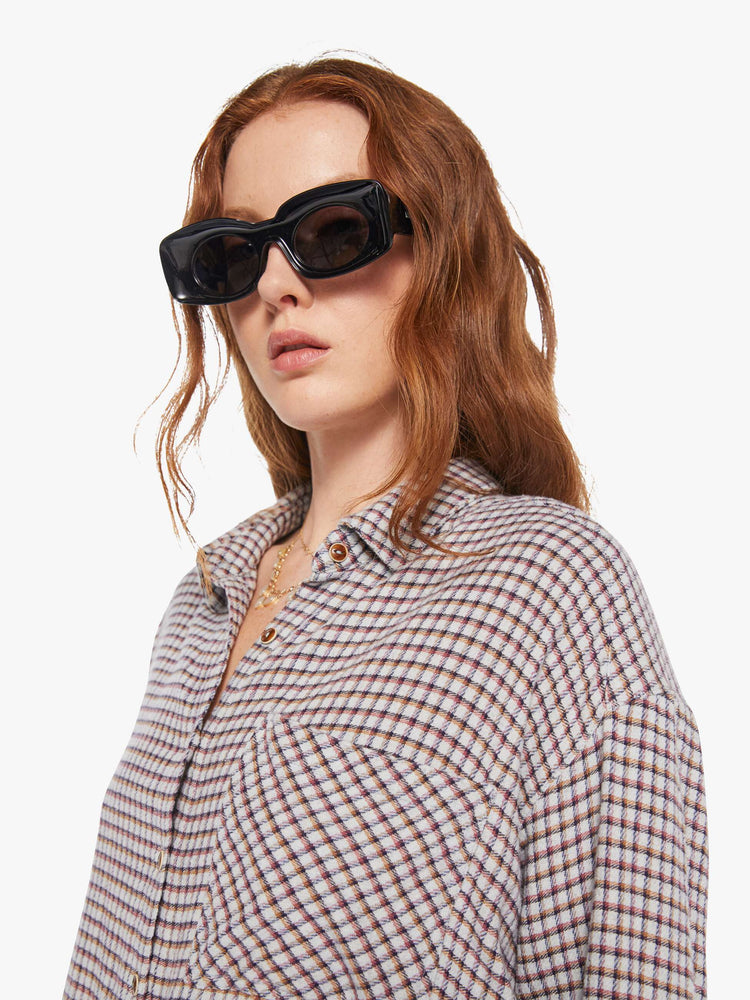 Cloe up view of a woman in a white and baby blue checker print long sleeve shirt is designed with drop shoulders, a front patch pocket, curved hem and slightly cropped fit.