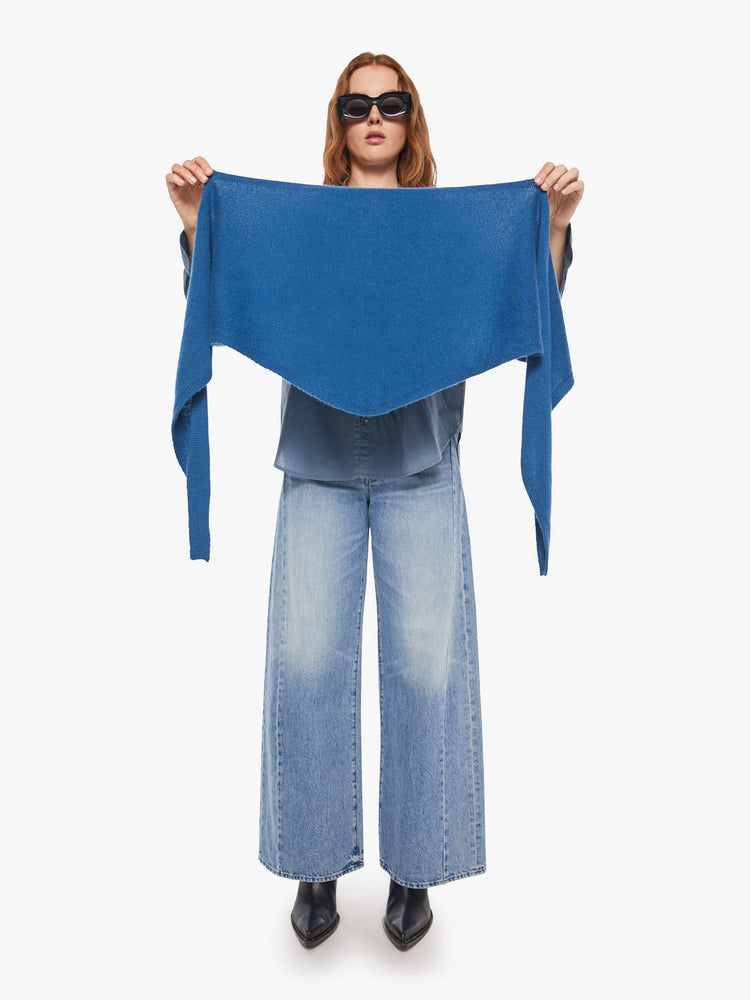 Front view of a model holding a cashmere blue scarf features a triangular silhouette with tapered ends.