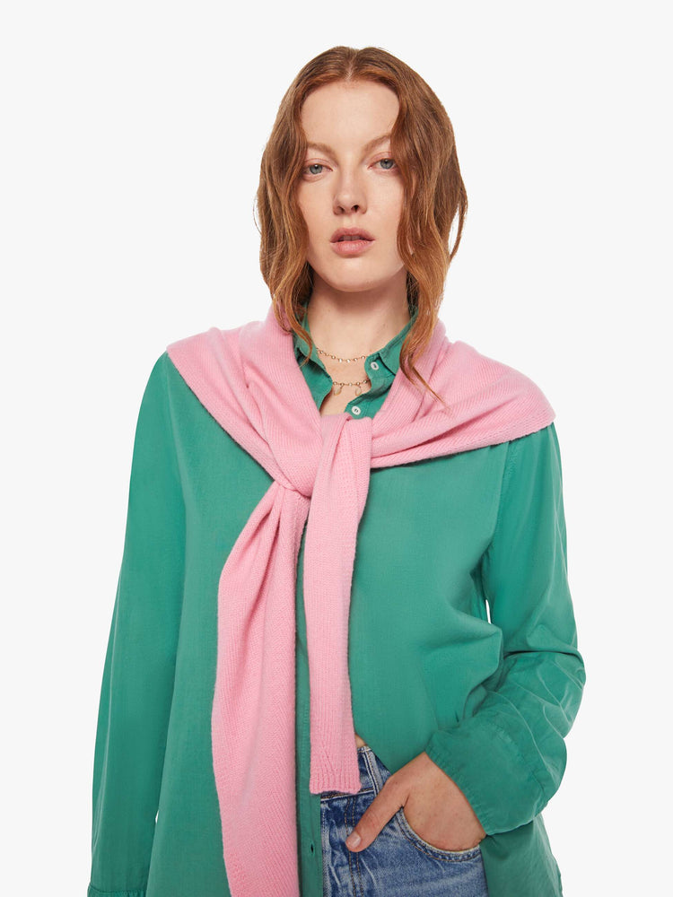 On model view of a woman in a cashmere  bubblegum pink scarf features a triangular silhouette with tapered ends.