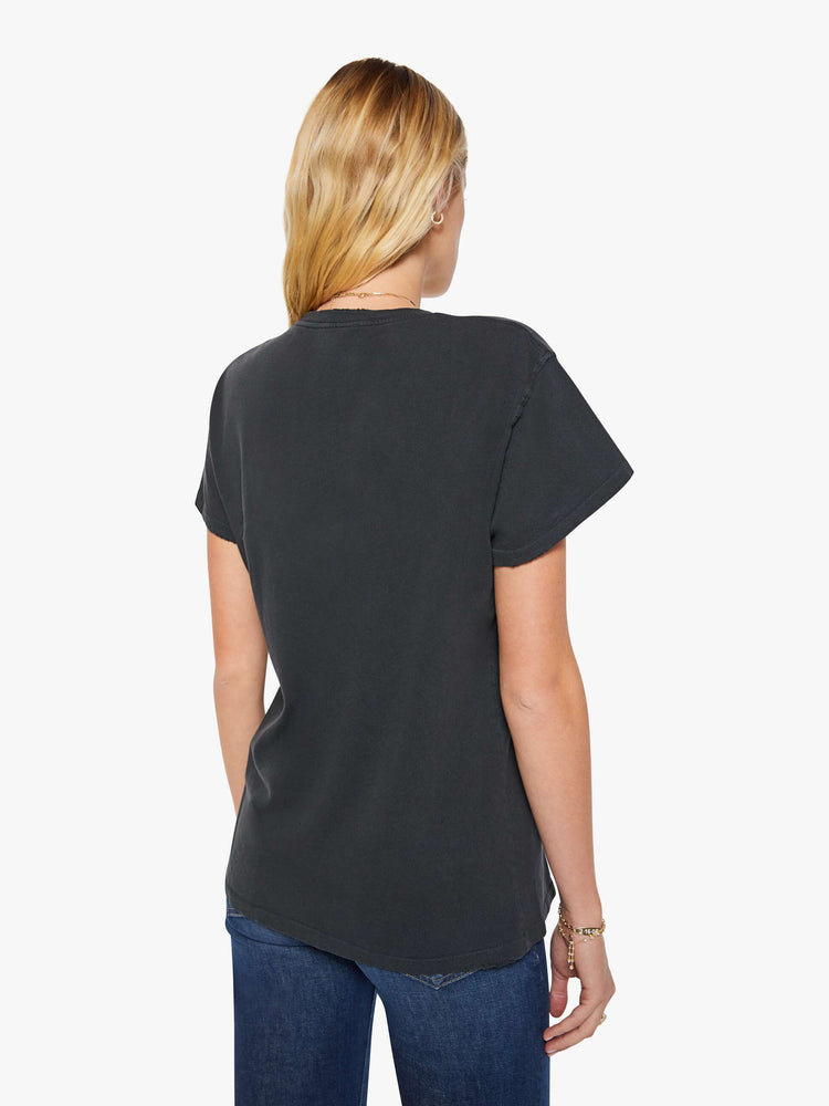 Back view of a woman in a black tee is inspired by Jimmy Buffett's American tour merch with a graphic portrait on the front.