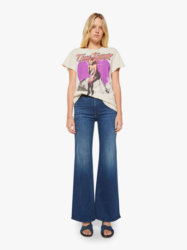 Full body view of a woman in a cream tee pays homage to Tina Turner with a graphic portrait on the front.