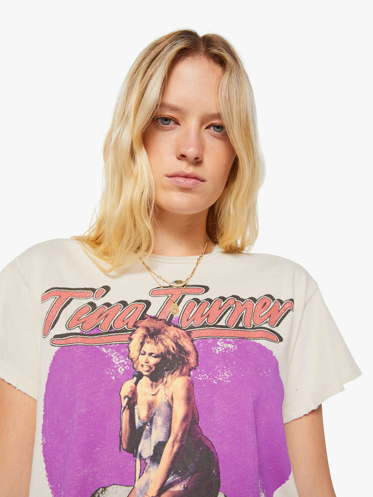 Close up view of a woman in a cream tee pays homage to Tina Turner with a graphic portrait on the front.