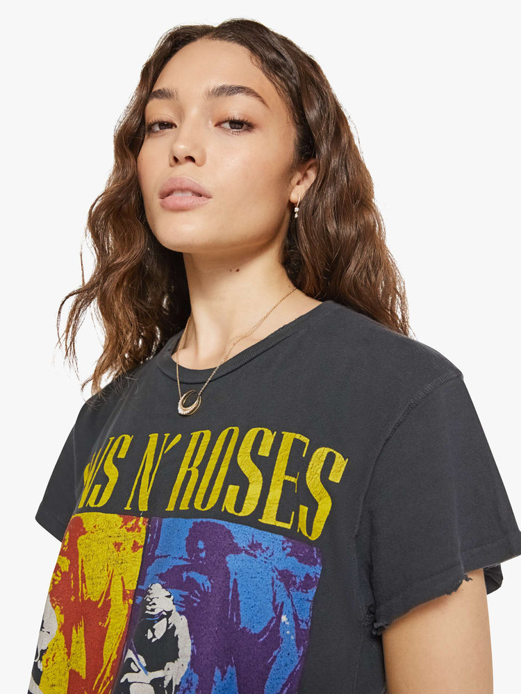 Close up view of a woman in a black tee that homage to Guns N' Roses with a graphic portrait and text in yellow on the front.