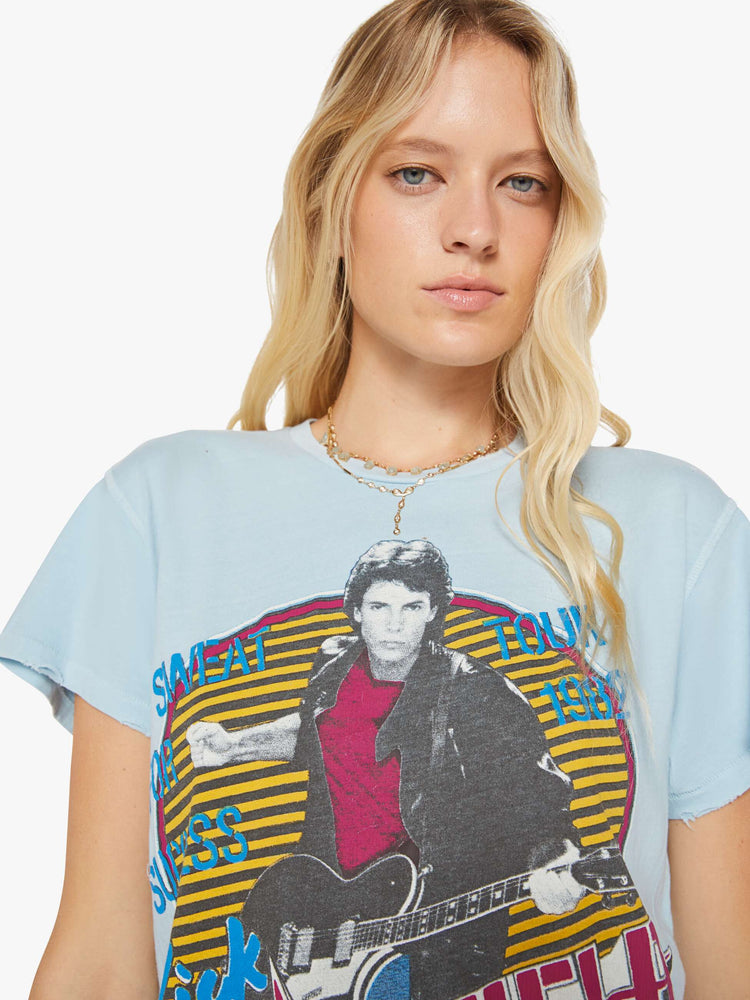 Close up view of a woman in a blue tee with a Rick Springfield with a graphic portrait on the front and back.