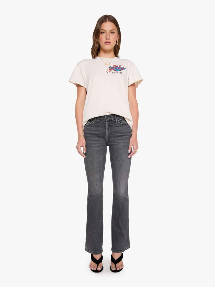 Full body view of a woman in a off-white tee pays homage to The Beach Boys with a colorful graphic on the front and back.