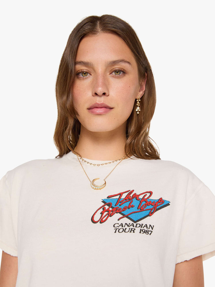 Close up view of a woman in a off-white tee pays homage to The Beach Boys with a colorful graphic on the front and back.
