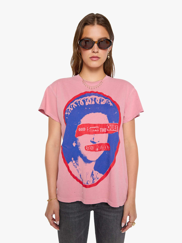 Front view of a woman in a pink tee pays homage to The Sex Pistols with a pop art-inspired graphic of the Queen of England in blue and red on the front. 