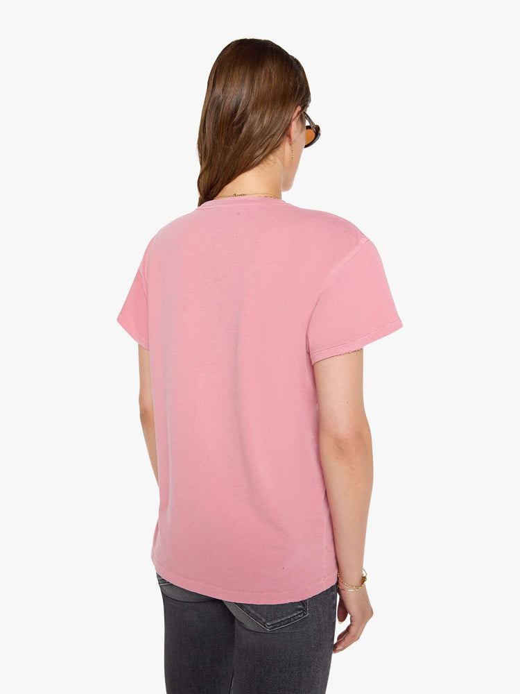 Back view of a woman in a pink tee pays homage to The Sex Pistols with a pop art-inspired graphic of the Queen of England in blue and red on the front. 