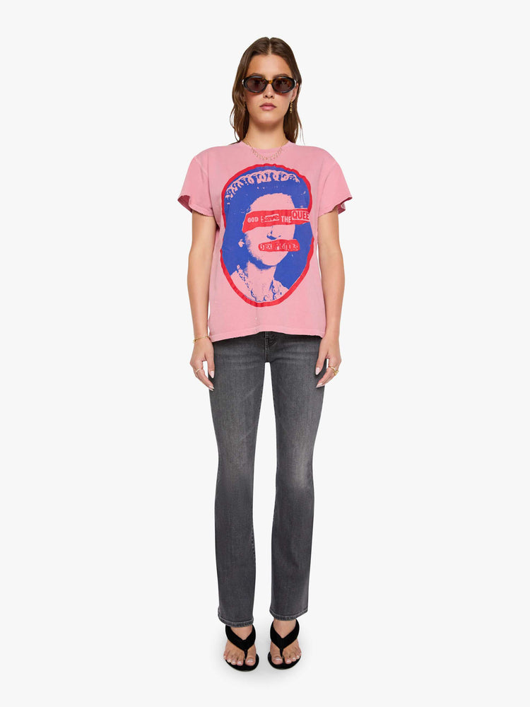 Full body view of a woman in a pink tee pays homage to The Sex Pistols with a pop art-inspired graphic of the Queen of England in blue and red on the front. 