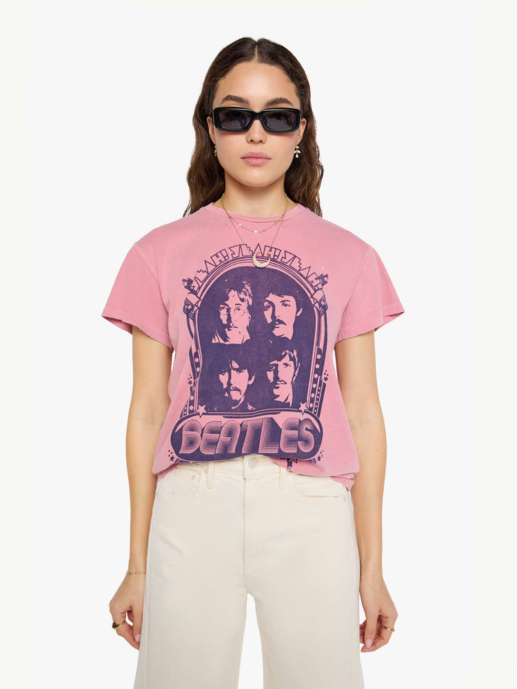 Front view of a woman in pinkvtee pays homage to The Beatles with a graphic portrait and text in blue on the front.