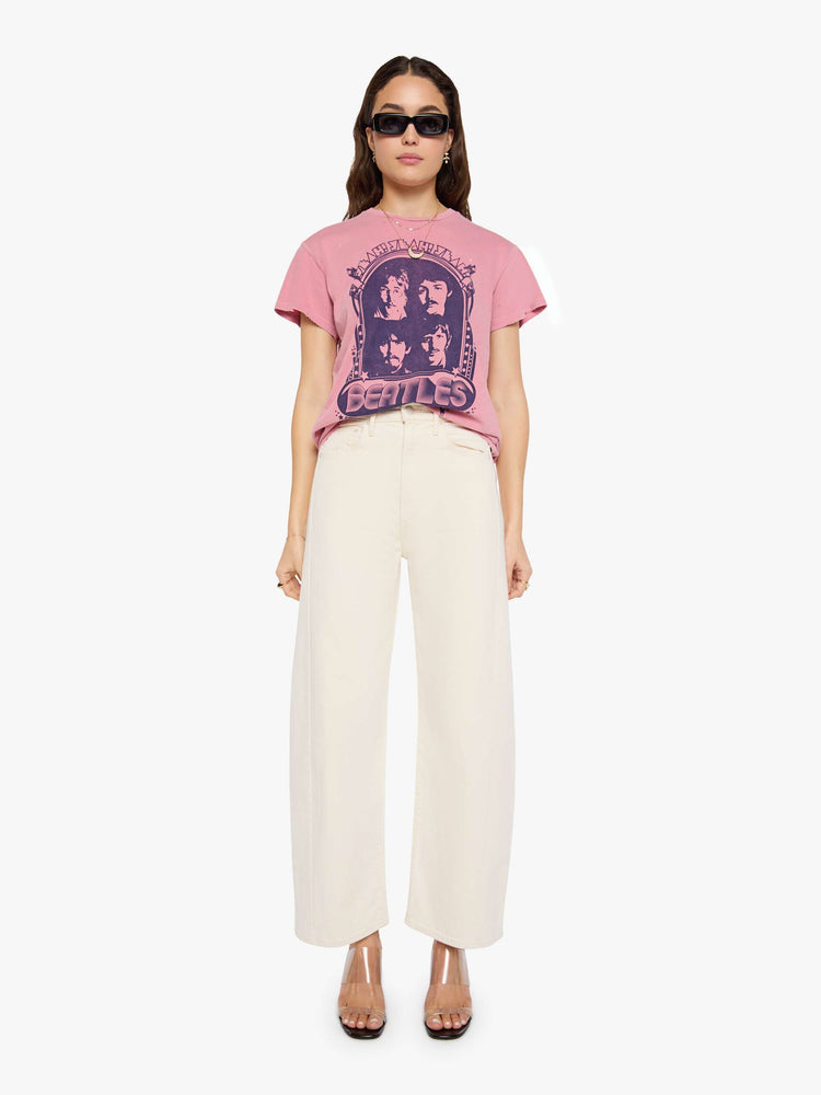 Full body  view of a woman in pink tee pays homage to The Beatles with a graphic portrait and text in blue on the front.