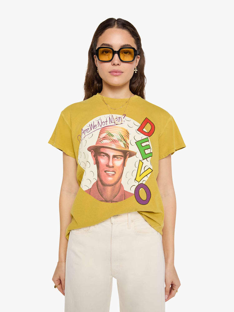 Front view of a woman in a yellow yellow the tee honors Devo with a graphic portrait and colorful text on the front.