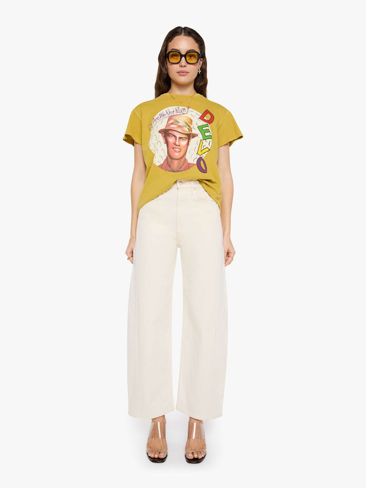 Full body  view of a woman in a yellow yellow the tee honors Devo with a graphic portrait and colorful text on the front.