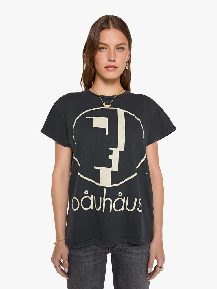Front view of a woman in black tee honors Bauhaus with a graphic portrait in cream on the front.