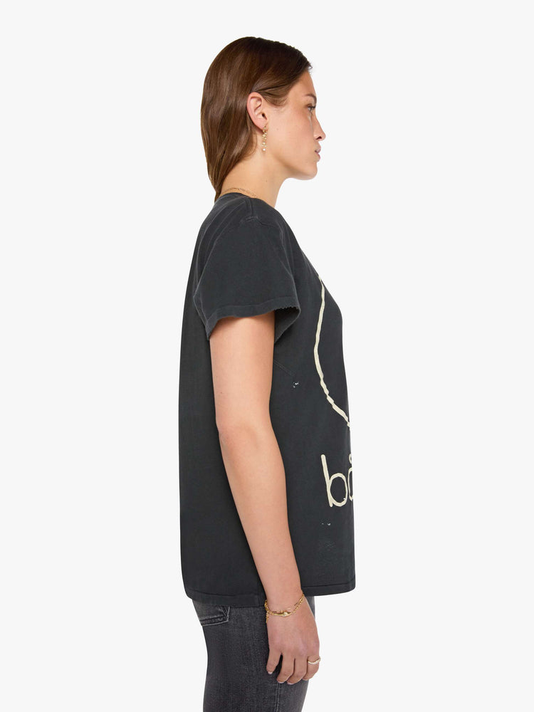 Side view of a woman in black tee honors Bauhaus with a graphic portrait in cream on the front.