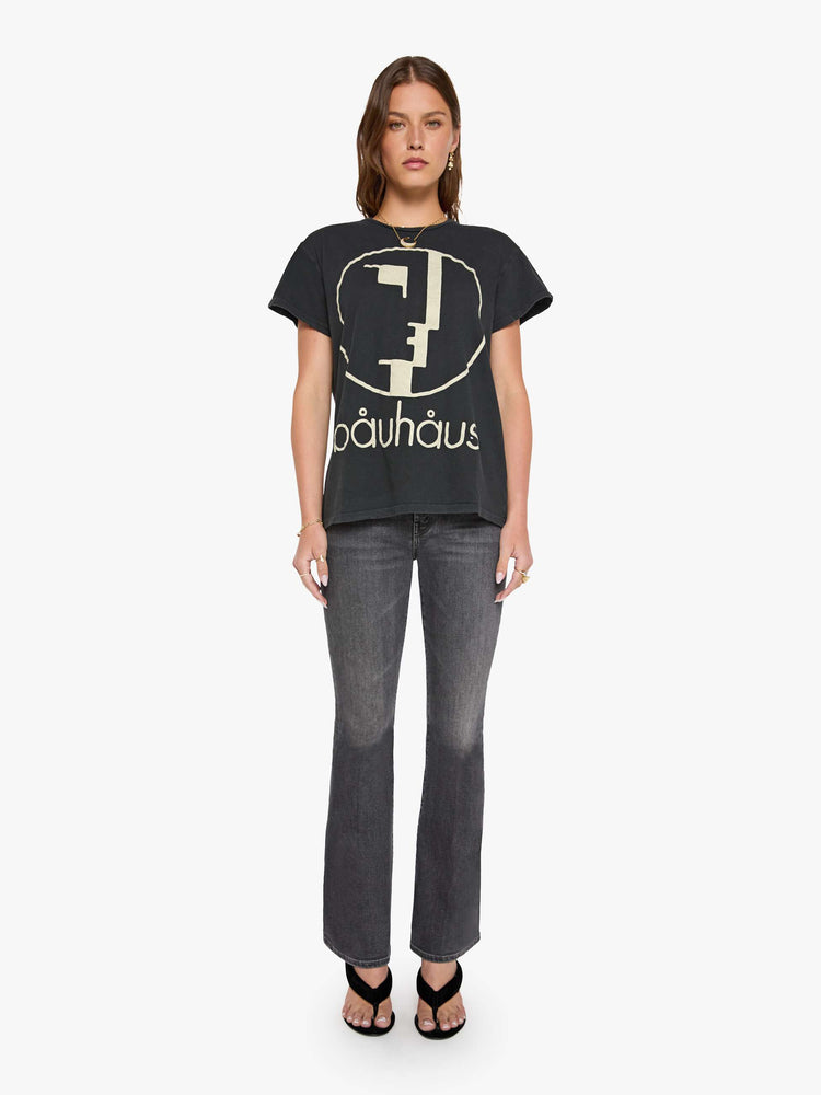 Front view of a woman in black tee honors Bauhaus with a graphic portrait in cream on the front.