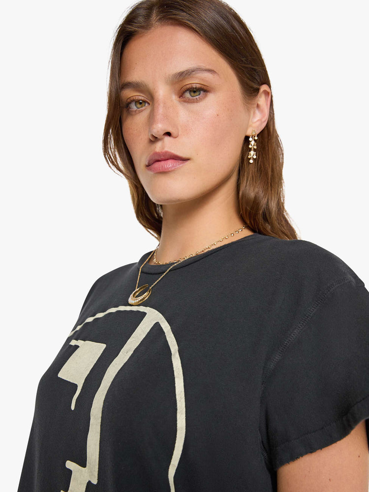Close up view of a woman in black tee honors Bauhaus with a graphic portrait in cream on the front.