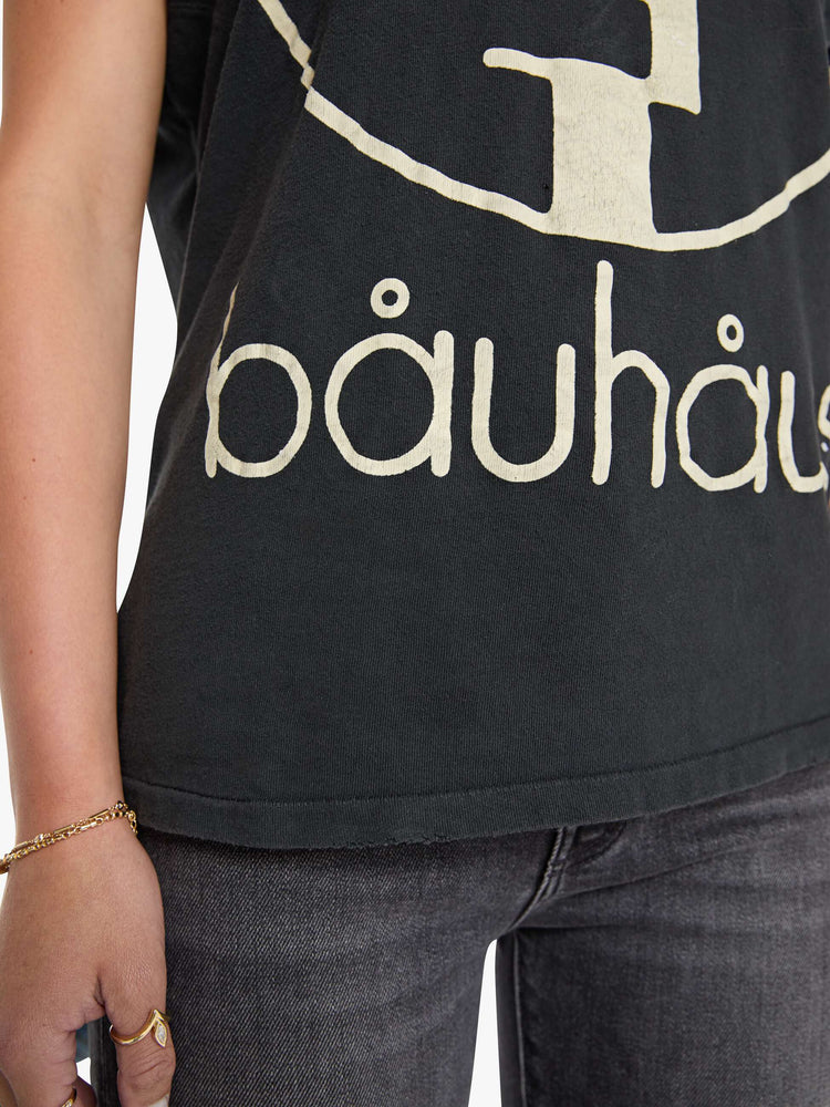 Close up view of a woman in black tee honors Bauhaus with a graphic portrait in cream on the front.
